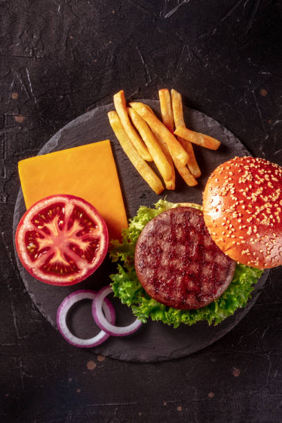 istock Beef burger ingredients, shot from above on a dark background 1353423279
