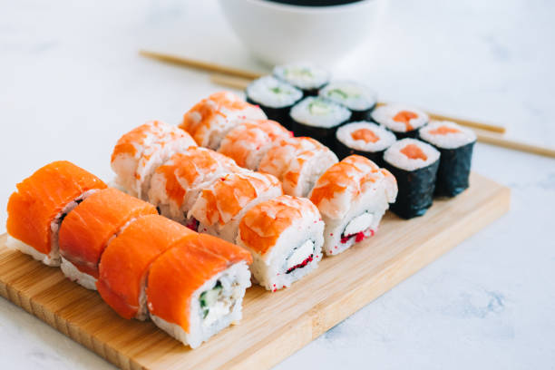 Sushi rolls set on bamboo board, Philadelphia, shrimp rolls and maki with soy sauce, Japanese food. stock photo