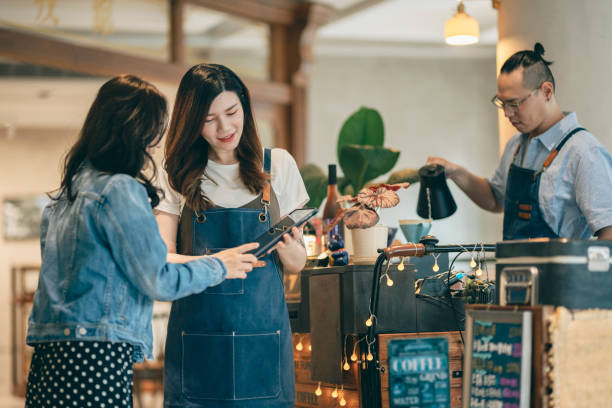 istock Cafe female owner serves customers, male owner makes coffee 1353423610