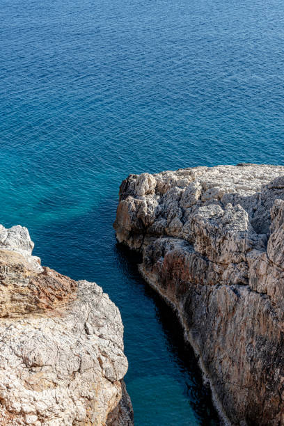 istock Small rocky cove in the blue sea 1353425187