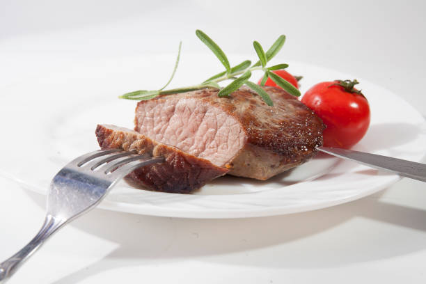 Appetizing steak well done on a white plate with tomatoes and rosemary stock photo