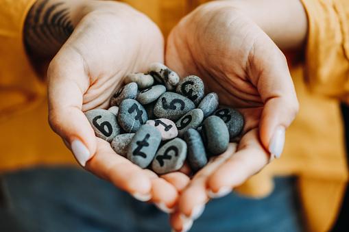 Numerology Numbers Concept. Numerology Calculate Life Path and Destiny Numbers. Many pebble stones with painted numbers in female palms.