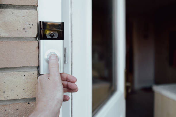 Shallow focus of a homeowner seen testing a newly installed WiFi smart doorbell. stock photo