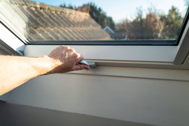 istock Shallow focus of a homeowner seen using a secure latch to lock a recently installed, double glazed skylight window. 1353428314