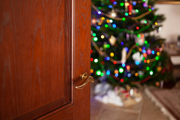 istock Open wooden door to room with christmas tree 1353433849