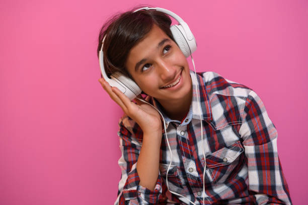 adolescente árabe usando fones de ouvido e ouvindo música fundo rosa - arab style audio - fotografias e filmes do acervo