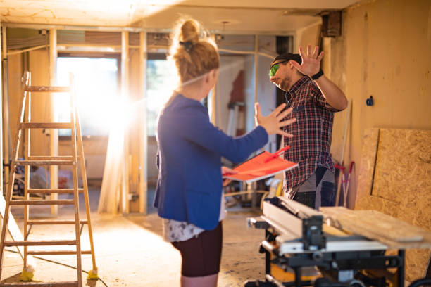 istock Young female architect talking to construction worker during home improvement inside of an apartment 1353436010