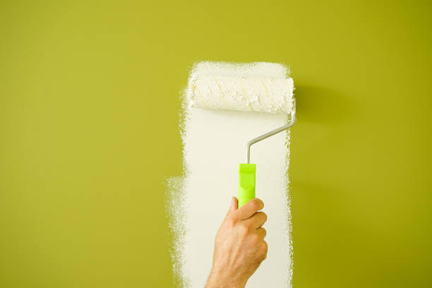 istock Male decorator painting wall with roller indoors, close-up. 1353436057