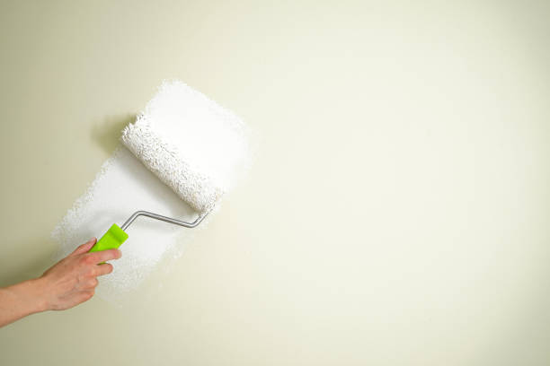 istock Male decorator painting wall with roller indoors, space for text. 1353436133