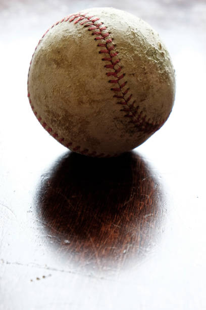 istock Old worn leather baseball on wood with light 1353436227