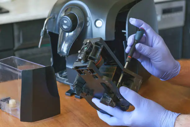 A repairman fixes a broken coffee maker, repair of household appliances