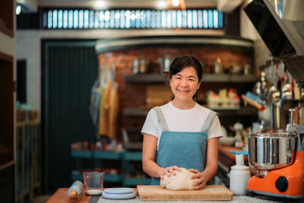 Asian chinese smiling baker women preparing dough in the kitchen stock photo