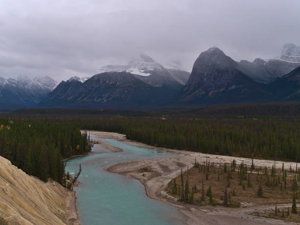 istock View over Athabasca River Valley in Jasper National Park, Alberta, Canada with dense coniferous forests and the snow-capped Rocky Mountains covered by clouds in autumn. 1353438724