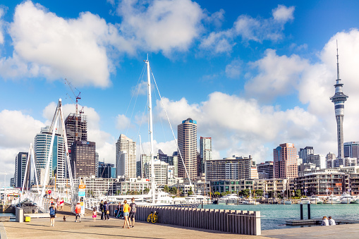 Auckland, New Zealand - People enjoying a warm and summer day in Auckland's Viaduct Harbour, with views across the city's CBD.