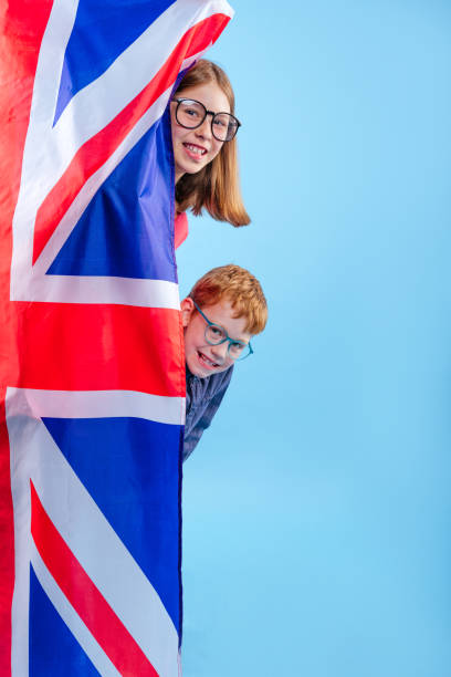 scolari che indossano occhiali da vista in piedi vicino alla bandiera union jack della gran bretagna - vertical caucasian glasses red hair foto e immagini stock