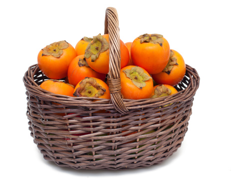 basket with persimmons on white