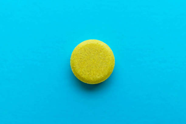 Yellow pill on blue background macro stock photo