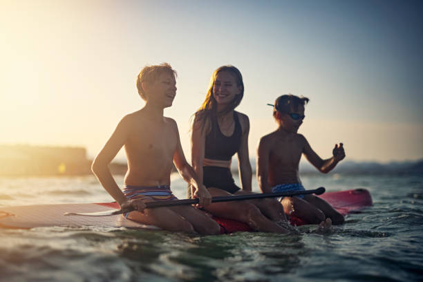 istock Three kids sitting on SUP paddleboard and having fun 1353444186
