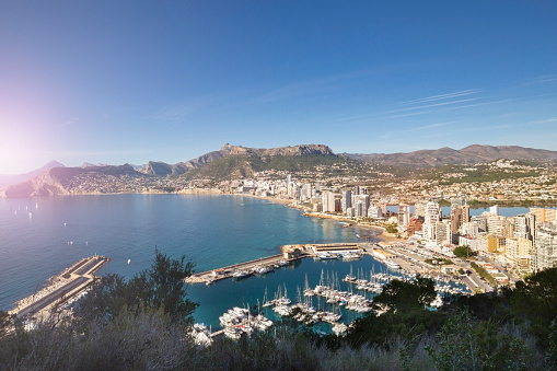 Coastline of the Mediterranean resort of Calpe, Spain with sea and yachts, lake, skyscrapers and mountain range
