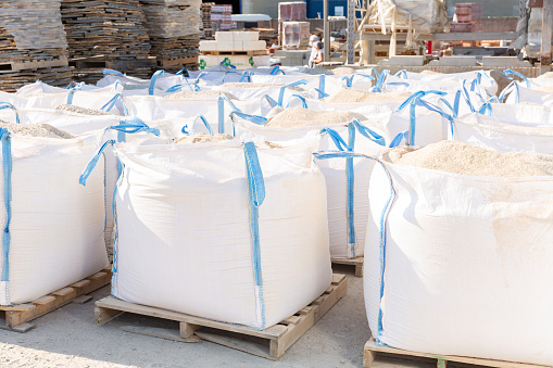 Image of bags with primer standing in a warehouse of building materials. Close-up image