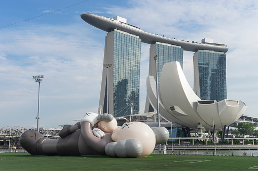 Singapore, Singapore - November 14, 2021: A large sculpture by the artist Kaws, set up on a floating platform before the Marina Bay Sands hotel.