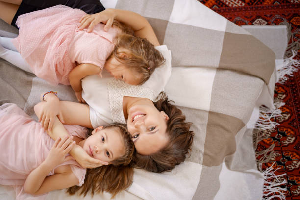 istock Mom spending her time with her daughters at home lying on bed 1353447398