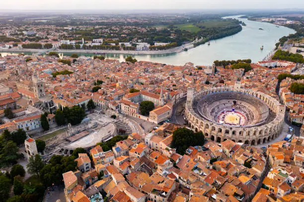 Cityscape of Arles, southern France. Tiled roofs of buildings, Arles Amphitheatre and Rhone River visible from above.