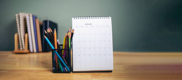 istock Desk for student education concept. Book, and pencil for study for exam. Calendar placed on School table with bookshelf and green wall background for student plan to work at home-panoramic banner 1353449625