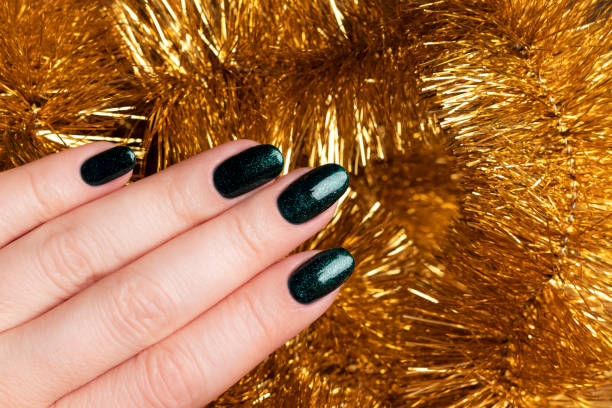 istock Hand with green glittered nails with golden tinsel 1353449817