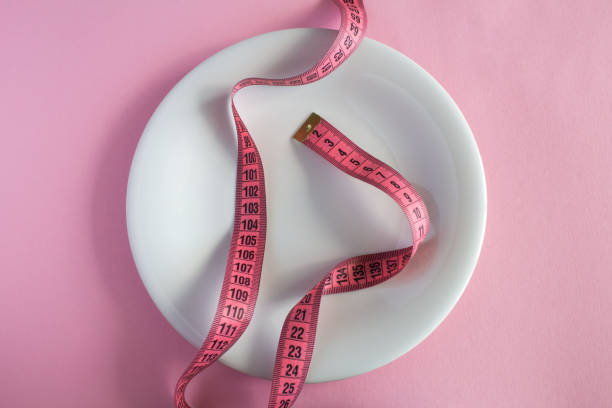 istock White plate and centimeter  on the pink  background. Top view. Close-up. 1353453797
