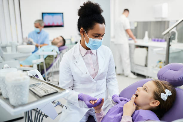 istock Small girl complaining about toothache during appointment at dentist's office. 1353453814