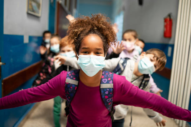 Group of school children wearing face masks in education center during Covid-19 pandemic. stock photo