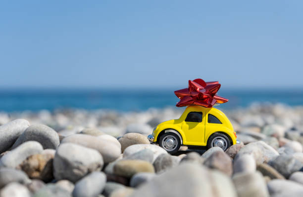 istock A yellow car with a red bow on its top standing on the seaside 1353456597