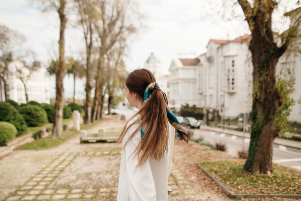 Rear view of a young woman in a city Rear view of a young woman in a city ponytail stock pictures, royalty-free photos & images