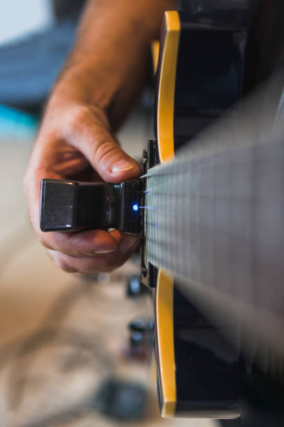 mano destra che tiene un ebow mentre suona una chitarra elettrica - ebow foto e immagini stock