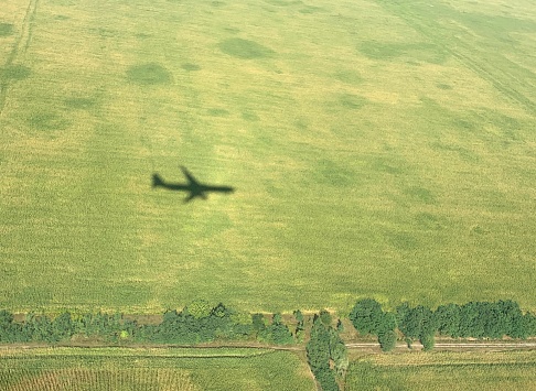 Airplane shadow over a green agricultural field on a summer day.