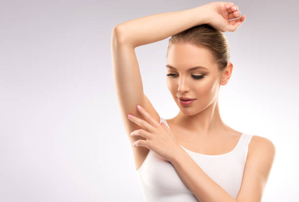 Young, woman dressed in sport bra is touching clean, soft skin of  armpit. Beauty, cosmetology and skin care. stock photo