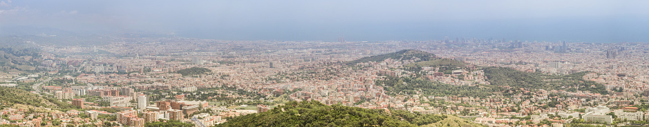 View of Barcelona from Mount Tibidabo, light clouds over the city. Summer has not yet reached full strength, so it is not very hot.