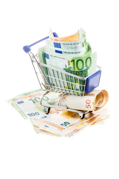 Photo of Shopping cart and Euro banknotes on white background