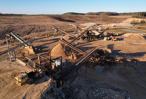 Mining dump truck unloads sand for crushing it into fractions at the crushing plant. Construction sand production near the quarry. Aerial view of an Mining work in open cast