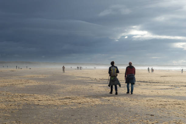 due uomini che passeggiano su una spiaggia coperta di alghe - ijmuiden foto e immagini stock