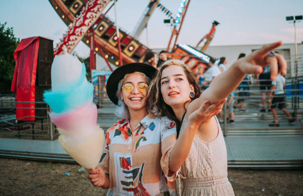 istock Happy girlfriends are eating cotton candy and make fun together 1353465618