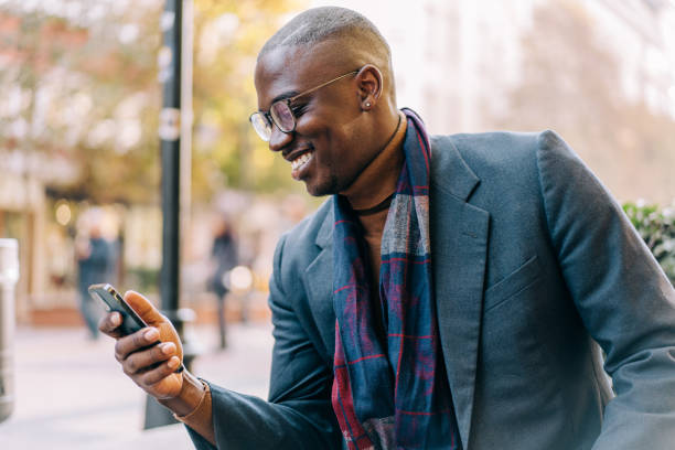 istock Young smiling man using smartphone on the street. 1353472348