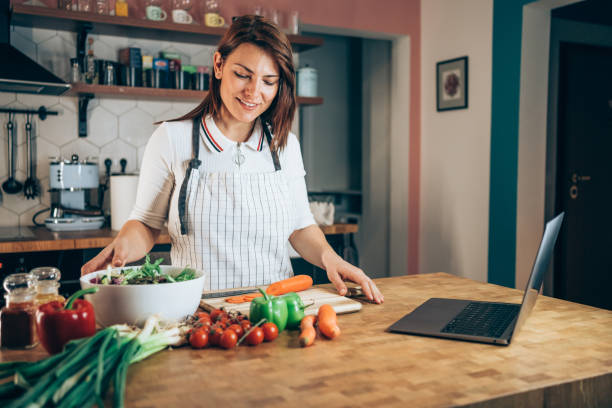 Woman cooking and using laptop in her kitchen.