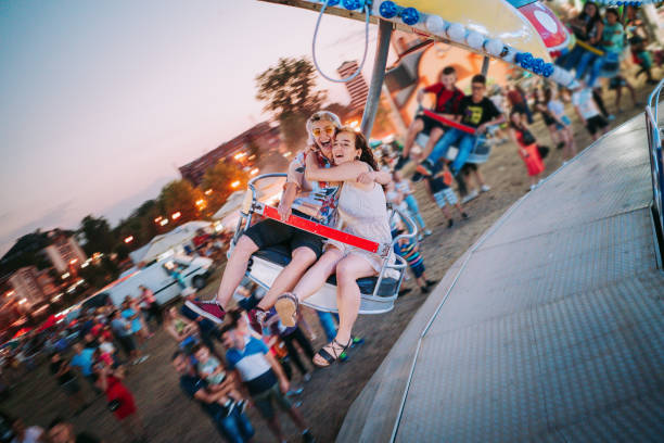 Spinning carousel with colorful metal chain swings set against background of green grass outdoors.
