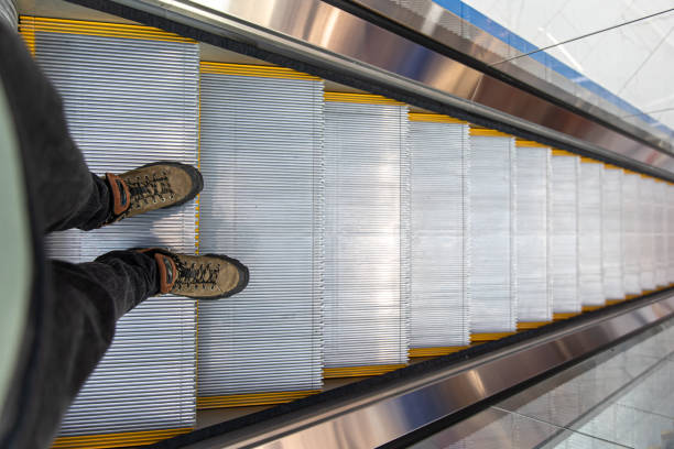 Male feet on an escalator in a shopping center, top view.