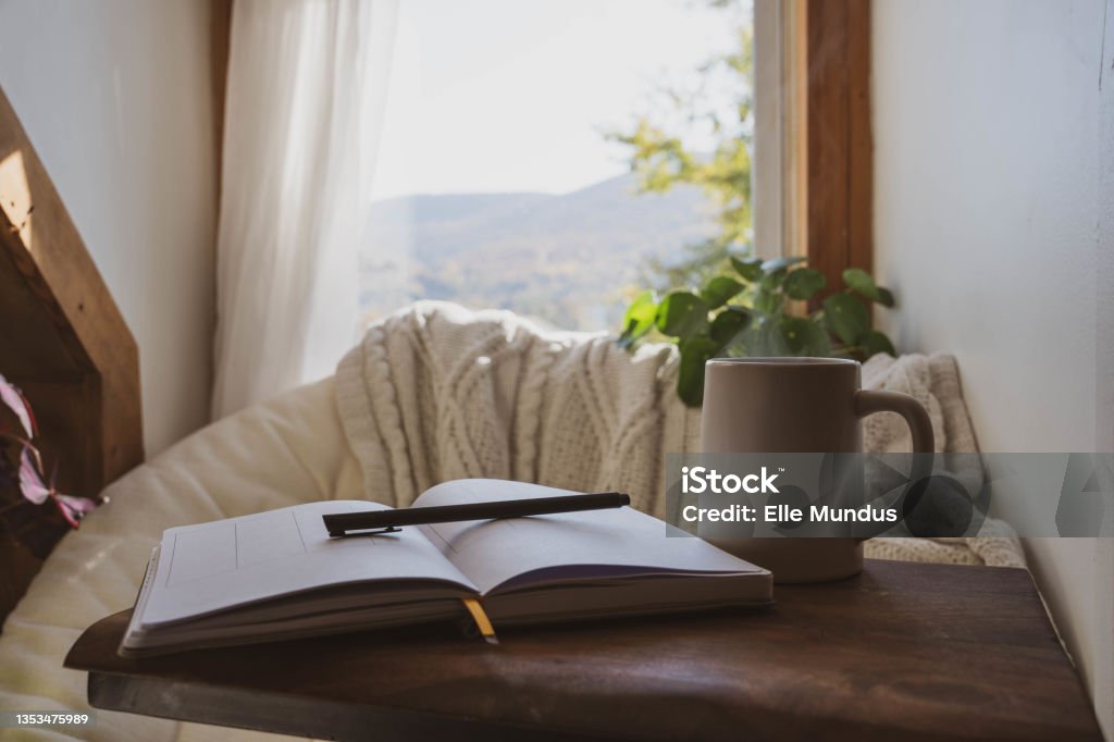 Cozy Window Nook with Open Journal And Coffee A cozy mental health break with an open journal, pen and coffee cup. Tranquility Stock Photo