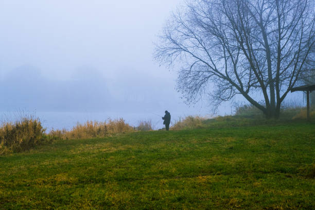 istock Fisherman on the pond in a fog 1353478089