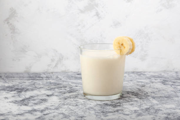 корейское банановое молоко в стекле на сером фоне. традиционное молоко со вкусом банана - smoothie banana smoothie milk shake banana стоковые фото и изображения
