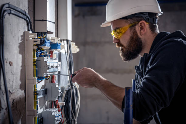 un elettricista maschio lavora in un centralino con un cavo di collegamento elettrico. - elettricista foto e immagini stock